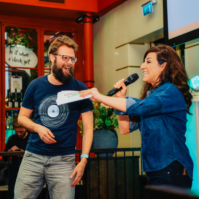 Raadsleden Bastiaan Bouwman en Melody Deldjou Fard presenteren met elkaar op het podium van een lokaal evenement.